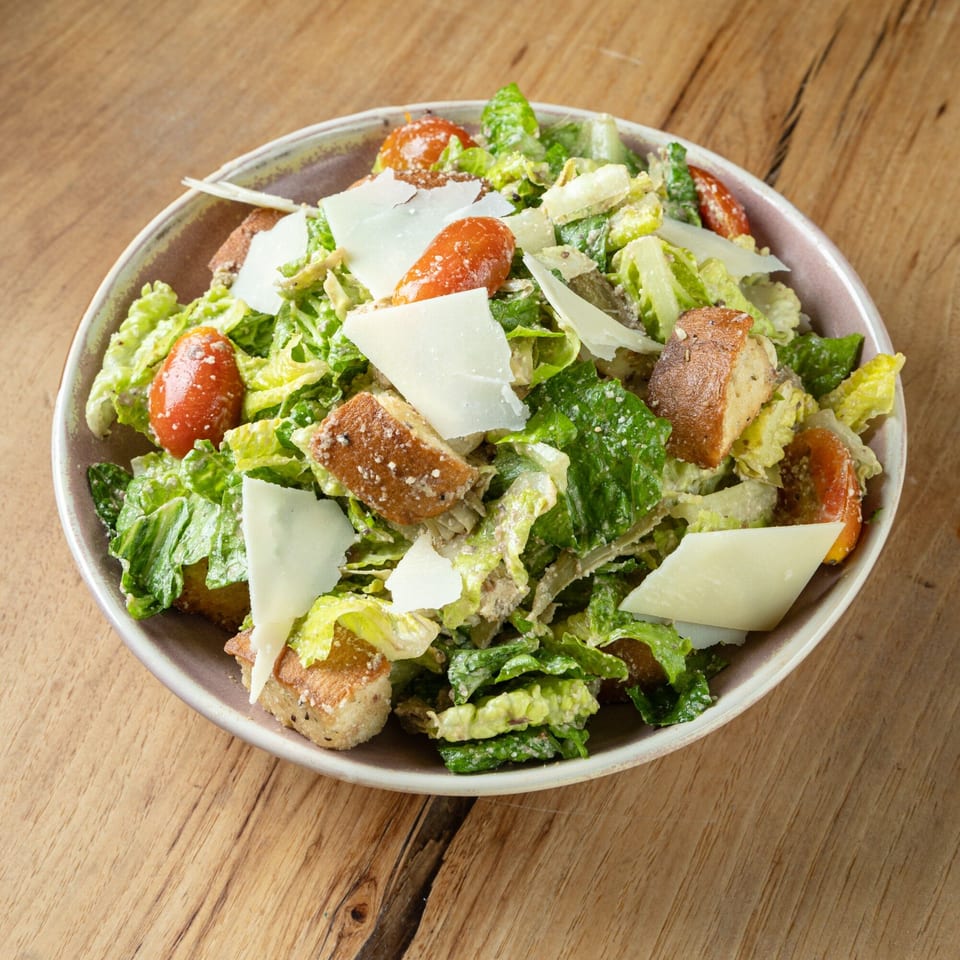 Caesar salad with romaine lettuce, cherry tomatoes, croutons, and parmesan cheese in a bowl.